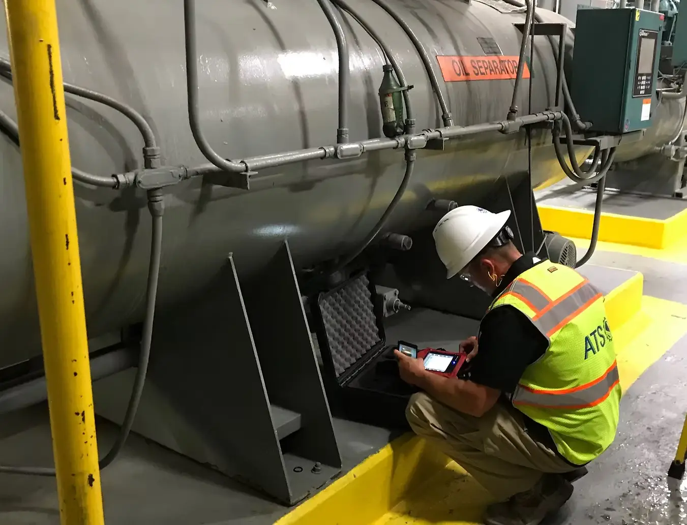 Oil Separator Maintenance & Safety Inspection | Industrial Equipment Check Technician in safety gear performing inspection on industrial oil separator unit using a digital device.